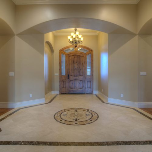 A gorgeous entryway in a new home featuring creative lighting fixtures and classic tile showcases the new home construction capabilities of Neil Adams Construction.